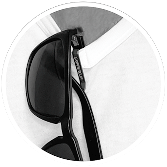 Black Electric sunglasses with GripperClip clipped and secured to men’s white vneck t-shirt